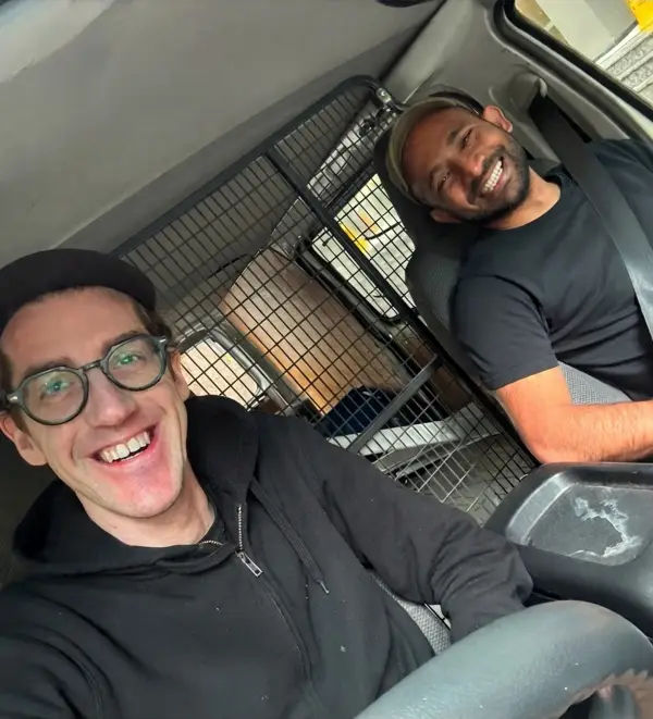 Niklas and Kogulan grinning from the front seats of a work van